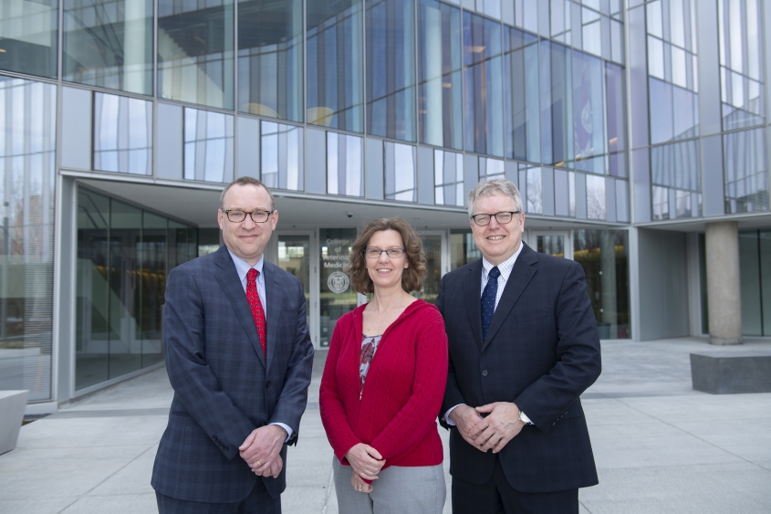 Three vet school administrators posing in front of the CVM building